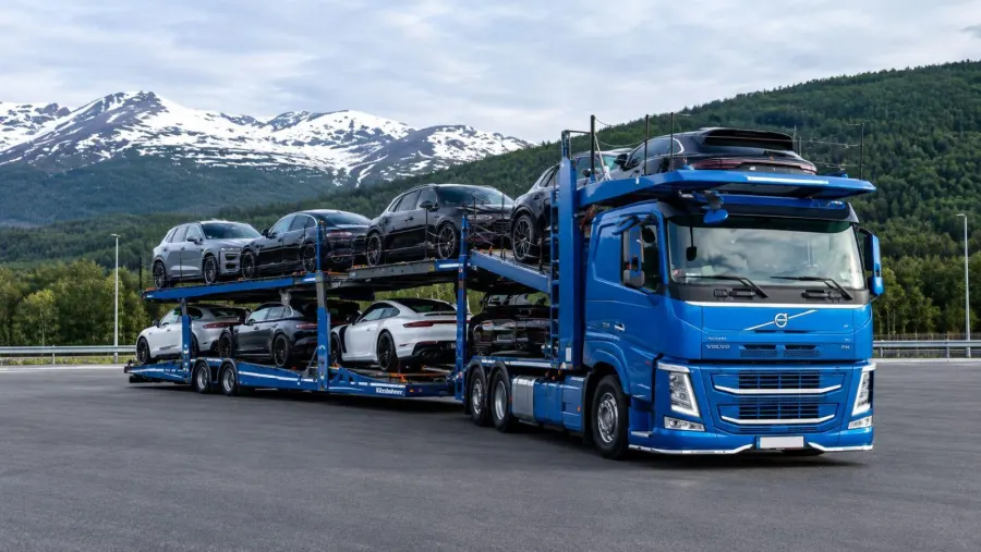 Mėlynas „Volvo“ autovežis su automobiliais kalnų fone